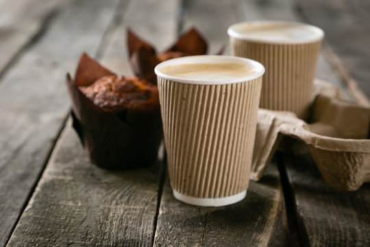 Coffee to go with muffin on wood background, copy space