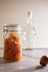 sauerkraut in a glass jar with carrot on a white background