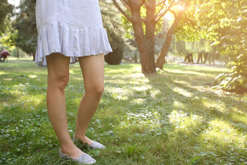 Stylish hipster girl in blue dress is standing outdoors on green grass. Summer photo.