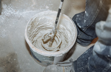Man is mixing spackling paste putty in the bucket. Grind of wall. Maintenance repair works...
