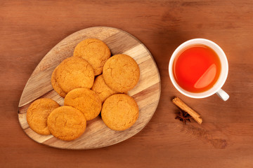 Spicy ginger cookies, shot from above with cinnamon and anise, and a cup of tea, on a dark rustic wooden background with copyspace