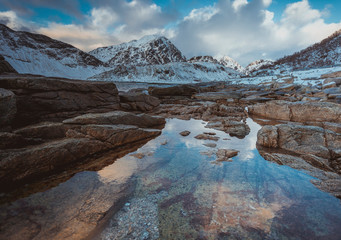 Rocky coast with beautiful mountains with reflection in the water in the winter on the Lofoten Islands in Norway