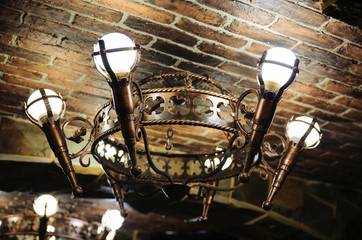 Fototapeta na wymiar Medieval lamp on the ceiling. Knight style chandelier decoration. Restaurant exterior.