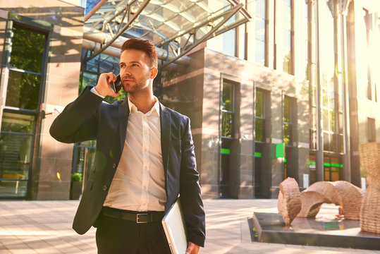 Young businessman standing in front of the office building and t