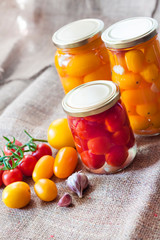 Glass jars with homemade pickled tomatoes, sealed with metal lid