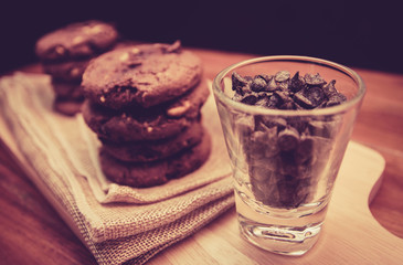 Chocolate chips in small glasses and cookies,vintage style tones.