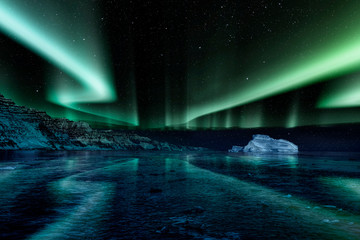 iceberg floating in greenland fjord at night with green northern lights - obrazy, fototapety, plakaty
