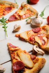 Sliced pizza top view.Italian pizza with tomato,meat,mushrooms and cheese on a rustic wooden table.Italian pizza on a dark wooden background. top view.