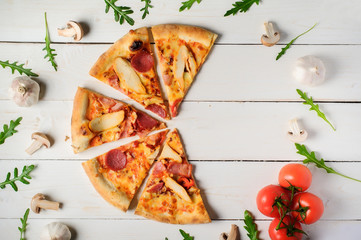 Sliced pizza top view.Italian pizza with tomato,meat,mushrooms and cheese on a rustic wooden table.Italian pizza on a dark wooden background. top view.