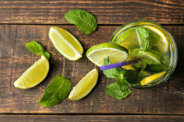 Mojito cocktail in a glass glass with lime, mint and lemon on a wooden brown table. top view