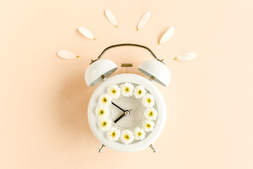 Fototapeta na wymiar Composition-summer time from clock and chamomile flowers on beige background. Flat lay, top view 