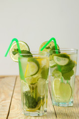 Mojito cocktail in a glass glass with lime, mint and lemon and on a natural wooden table. make a mojito.