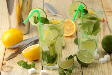 Mojito cocktail in a glass glass with lime, mint and lemon and bar accessories on a natural wooden table. make a mojito.