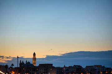 Fototapeta na wymiar Panoramic view of cityscape in Bari, Italy. Romantic, calm, relaxing evening in city. Sun is setting over old town. Silhouette of cityscape.