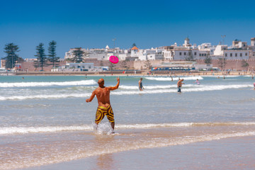 Mężczyzna bawi się różowym fisbee na plaży