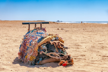 Oryginalne siodło wielbłąda leży zdjęte na piaszczystej plaży - obrazy, fototapety, plakaty