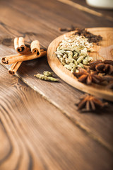 Seasoning on a textured wooden background close-up and copy space. Cinnamon, star anise, fennel, cloves, seasoning tea masala as a texture