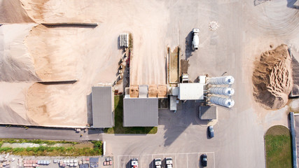 Aerial shot of asphalt and cement factory. Large piles of construction sand, gravel, limestone quarry, mining rocks used for asphalt production, building. Heavy machinery in parking lot ready to work