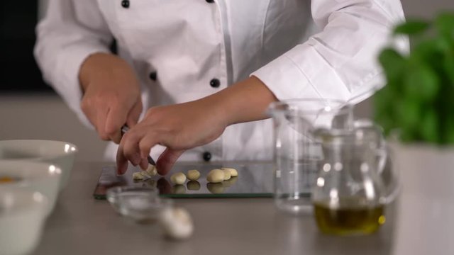 4K food video, detail shallow focus female cook woman cutting fresh garlic in kitchen