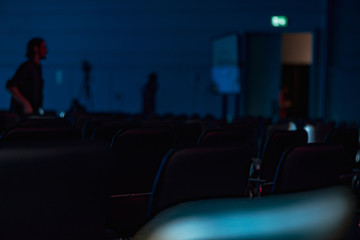 Interior of a conference hall. Chairs in the dark hall. Dark, empty hall with comfortable seats in blue light. Close up for seat rows in movie theatre