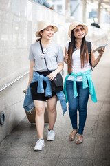 Naklejka premium Two happy asian girls dragging luggage suitcase bag. Travel concept.