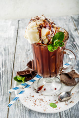 Iced chocolate cocktail. Cold summer sweet drink with cocoa, vanilla ice cream ball and mint leaves. wooden background copy space
