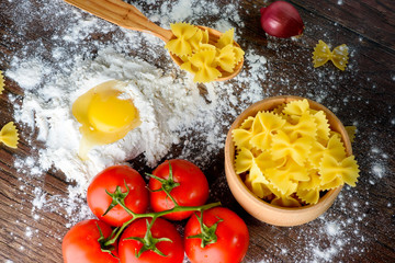 pasta italian farfalle ingredients, tomatoes, eggs, flour, rustic background.