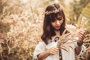A portrait of a asian beautiful hippie girl in white dress on a field. Bohemian Style.