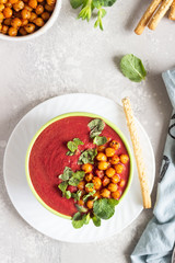 Spring detox beetroot soup with mint, coconut milk and baked chickpeas on a light grey concrete background, copy space. Dieting, clean eating, weight loss, vegetarian food concept.