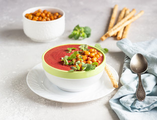 Spring detox beetroot soup with mint, coconut milk and baked chickpeas on a light grey concrete background, copy space. Dieting, clean eating, weight loss, vegetarian food concept.