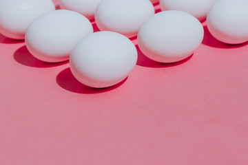 White chicken eggs  with empty space, on a pink background. Abstract image