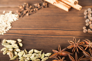 Seasoning on a textured wooden background close-up and copy space. Cinnamon, star anise, fennel, peppercorns, cloves, tea masala seasoning as a texture