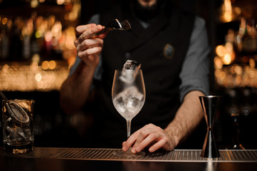 Bartender throwing to a cocktail glass one big ice cube