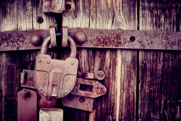Padlock on a wooden door. Old unpainted gates with metal brackets and lock.