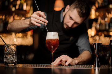 Professional bartender stirring a delicious cocktail in the glass