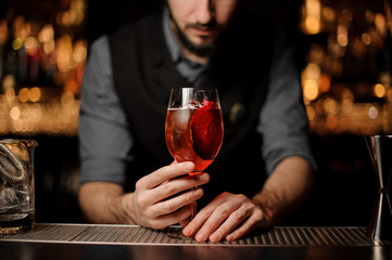 Professional bartender serving a delicious cocktail with a decor of red slice