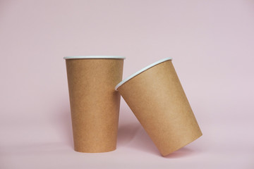Coffee cup on pink paper background. A couple of paper cups of coffee to take away.