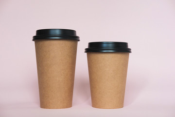 Coffee cup on pink paper background. A couple of paper cups of coffee to take away.