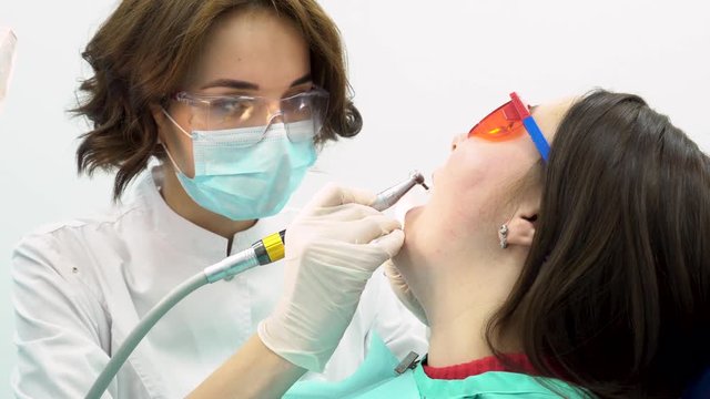 Close up for a woman dental doctor treating female patient, medicine concept. Woman dentist in uniform with dental equipment during working process.