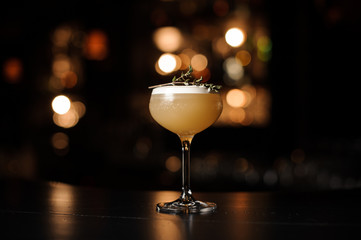 Delicious yellow cocktail in the glass decorated with a smoked herb