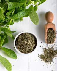 Dried peppermint in a white bowl and a bunch of fresh mint, on wooden background. Food background. © ozgur