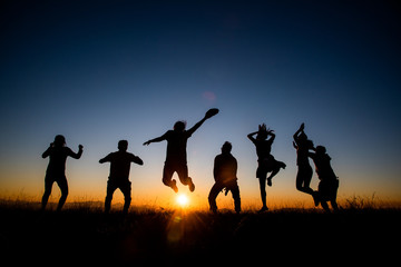 Silhouettes group of people on  mountain with sunset