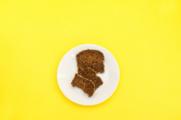 Sliced rye bread on the white plare and yelow background. Whole grain rye bread with seeds