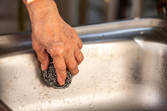 Senior Woman's left hand using steel wool for cleaning sink Close up shot, Selective focus, kitchen concept