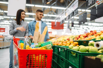 Couple with cart in supermarket, fruits department