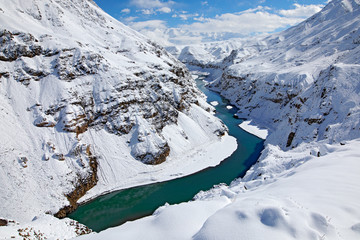 Indus river in Hemis NP, Ladak, India. River with snow during winter, Himalayas. Mountain landscape in India wild nature. Sunny day with snow in the valley, blue sky with white clouds.