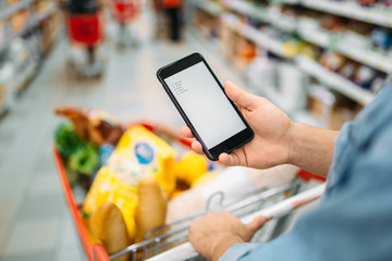 Man with trolley makes a purchase by the list