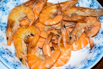 huge boiled red king prawns lie on blue plate dish