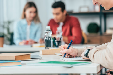 Obraz premium Cropped view of student writing in notebook in classroom