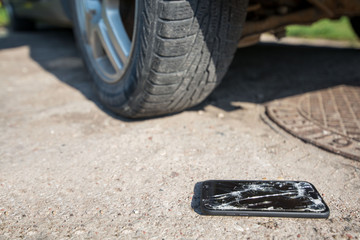 Broken and damaged smartphone with cracks on glass screen laying on ground. Accident. Cell phone...